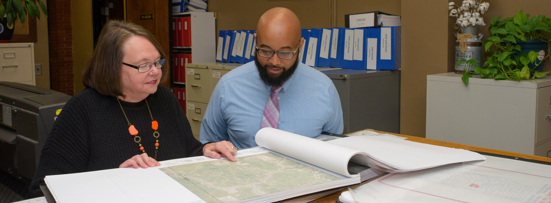 Man and woman looking at maps in office.